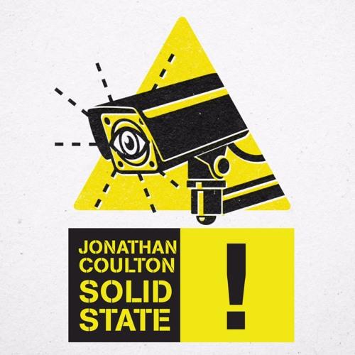 Yellow triangle with security camera with an eye on the screen above black words on yellow saying Jonathan Coulton Solid State excalamation point