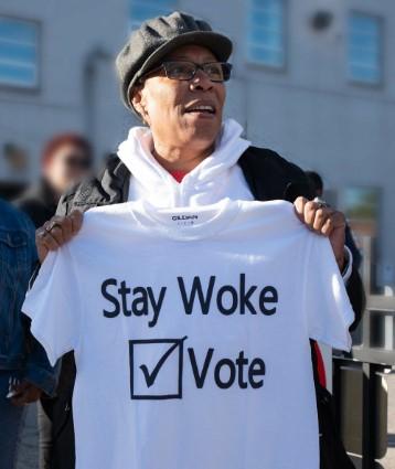 Woman holding T-shirt saying Stay Woke Vote