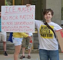 White woman in Black Lives Matter Tshirt holding a sign that says ICE murders