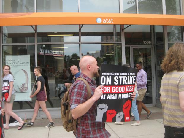 Guy in a strike protest holding a sign that says On Strike