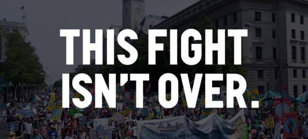 Black and white background of people at a rally and the words THIS FIGHT ISN'T OVER