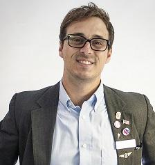 Travis Irvine in a suit and glasses