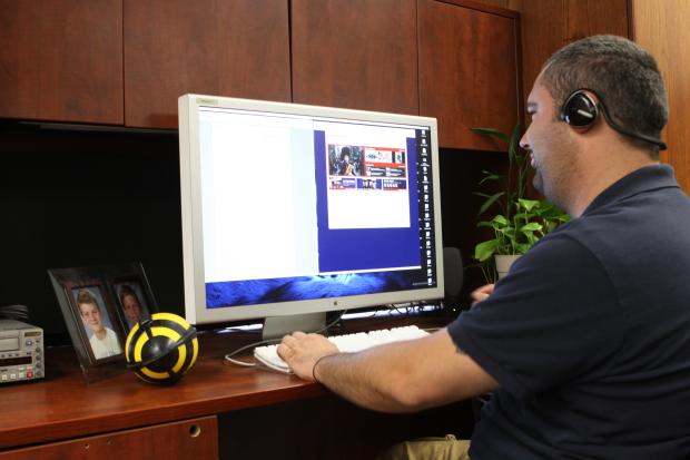 Man sitting at desk with headphones working on a computer