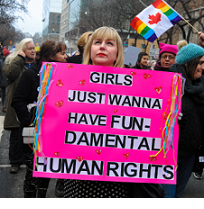 Women marching and young blonde woman holding a pink sign that says Girls Just Want to Have Fun-damental Rights