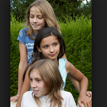 Three young white girls with one above the other looking down