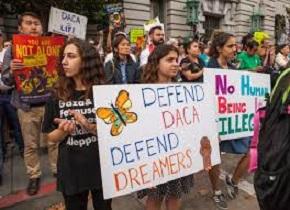 Young people holding signs outside a building that say Defend DACA Defend Dreamers