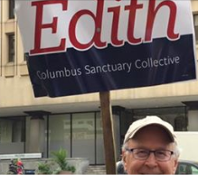 Man holding sign on stick that says Edith Columbus Sanctuary Collective