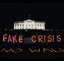 PHoto of white house with neon lights in front against black saying FAKE CRISIS NO WALL
