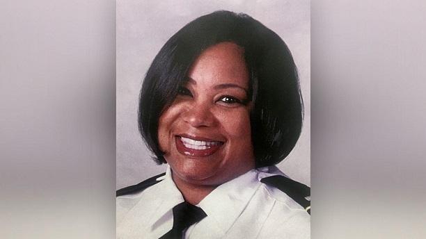 Head shot of black woman with short black hair smiling wearing a police uniform