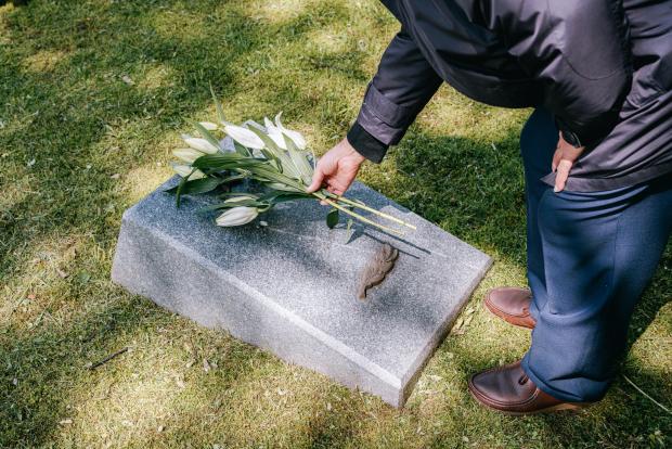 Person putting flowers on a gravestone