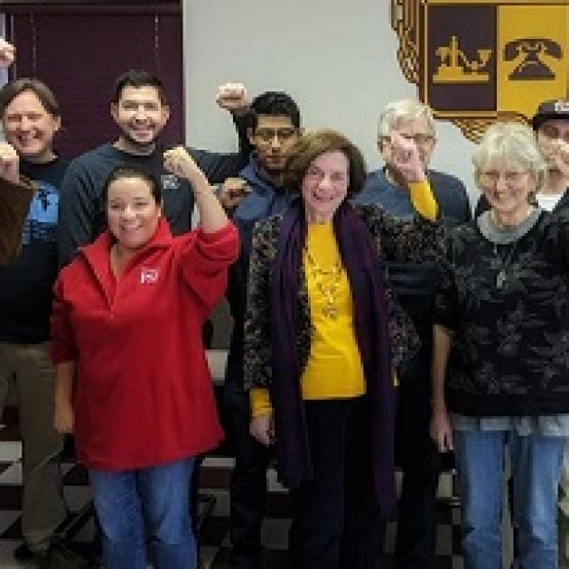 White and Latino people posing and holding their fists in the air