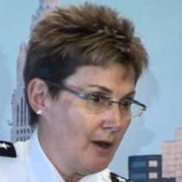 White women with glasses and short brown hair wearing a police uniform looking surprised