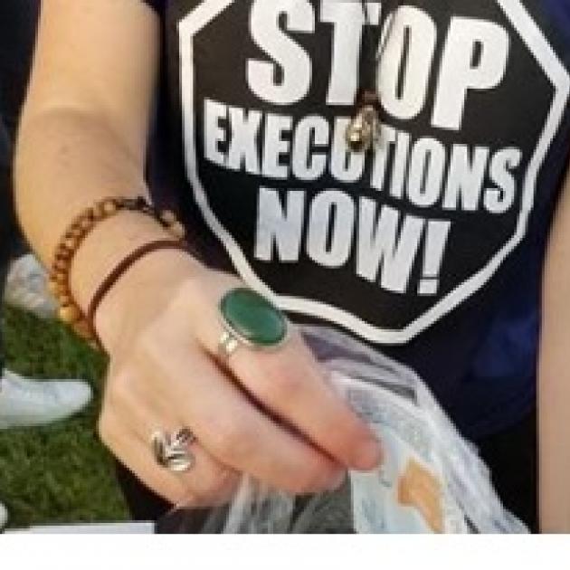 Woman from neck down wearing black T-shirt with words Stop Executions Now