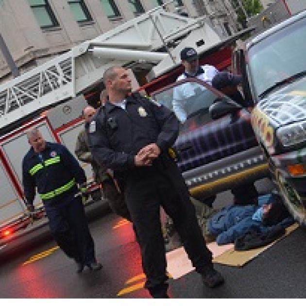 Cops and person lying on ground next to a car with a fire truck