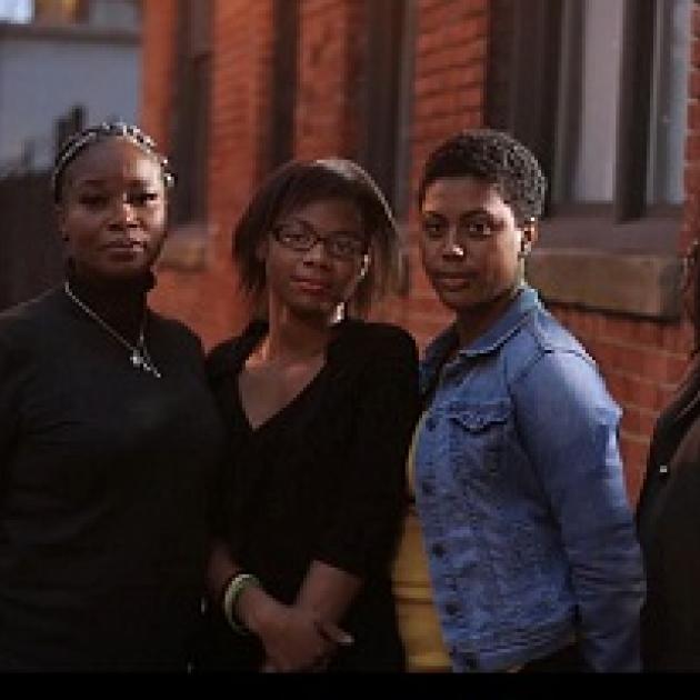 Three black women standing outside a brick building