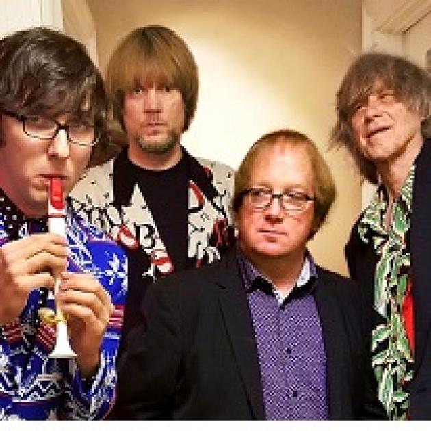 Four white guys one playing a kazoo and looking like rock stars except one guy in the middle with a sport coat on