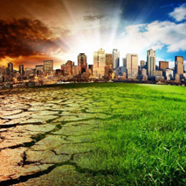 A cityscape against a horizon with sunrays shooting from the ground to a blue sky on right and fiery sky on left with the fore ground at right green grass and at left cracked and dry