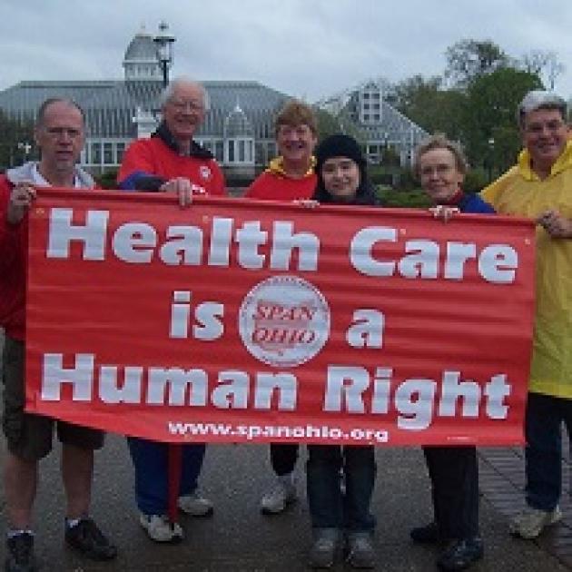 People holding a red sign that says Health Care is a Human Right 