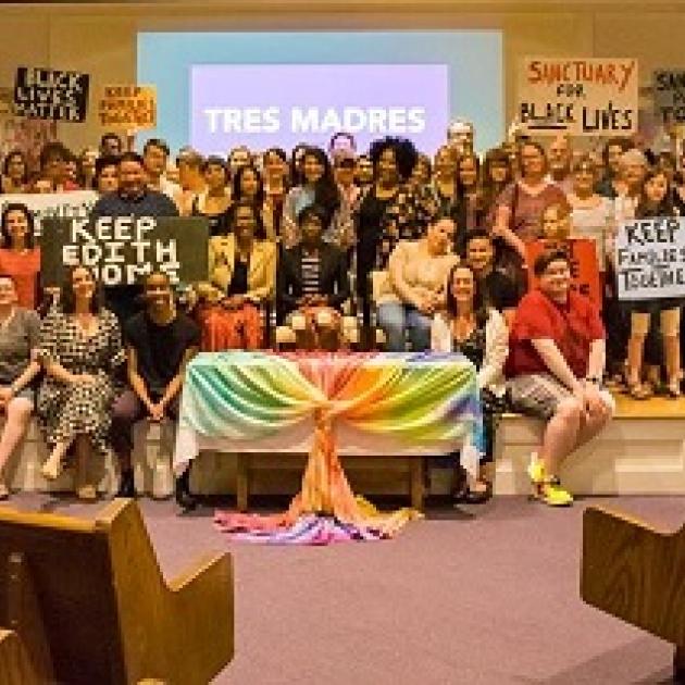 Many people posing inside a church with colorful banners and sign  about Keep Edith Home