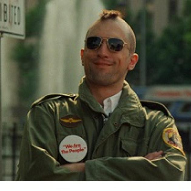 Robert De Niro, youngish white man with a mohawk hairsut and sunglasses smiling with his arms crossed, wearing an army jacket with patches