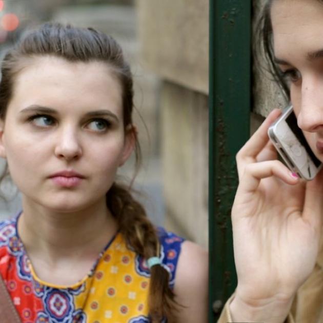 A woman on the phone and another woman looking at her in an alarmed way