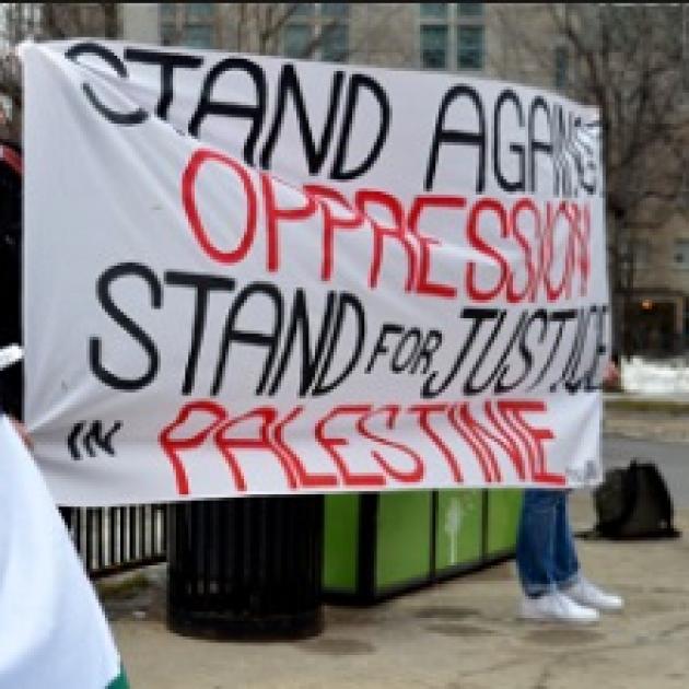 A big sign on a sheet saying Stand Against Oppression Stand for Justice for Palestine