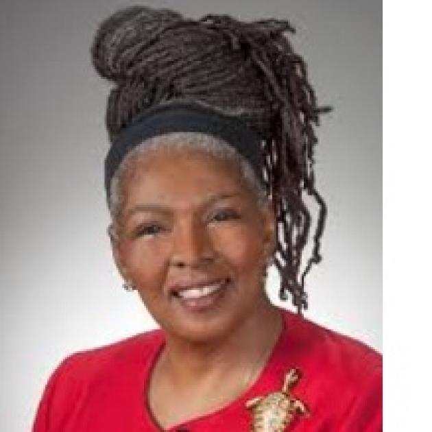 Black woman head and shoulders, smiling with red suit and high hair