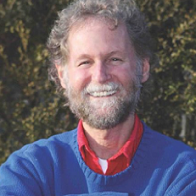 Smiling white man head and shoulders, he has mustache and beard and blue sweater