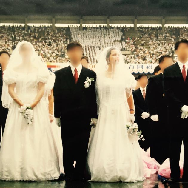 Two couples, grooms in black suits and women in long white wedding dresses