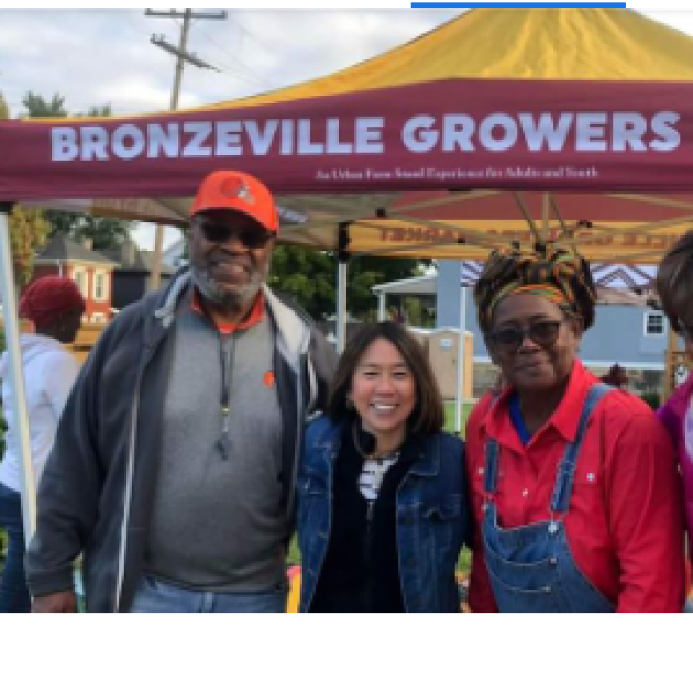 People posing in front of a Bronzeville Growers Market sign