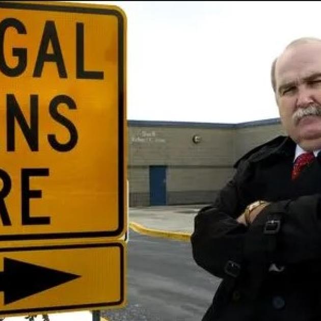 SIgn saying illegal aliens here and a stern bald older man with arms crossed and 