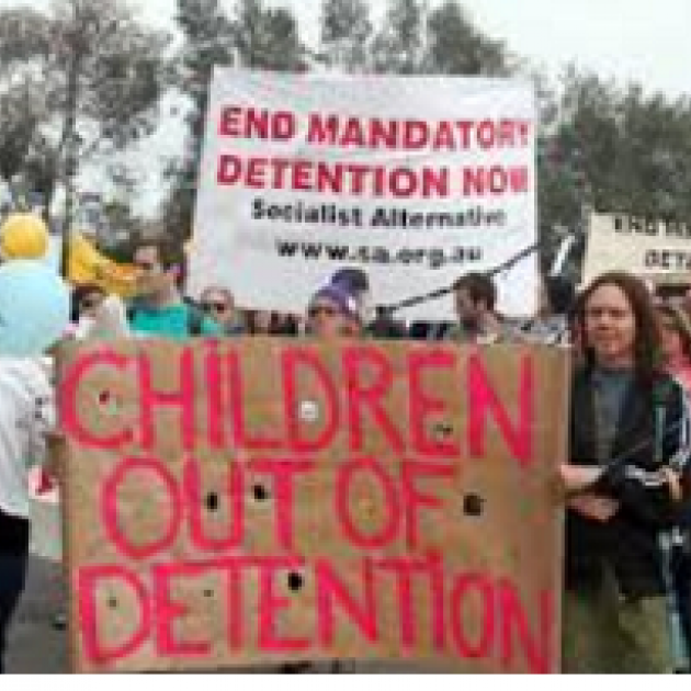 People outside at a rally holding signs saying Children out of detention and End Mandatory Detention Now