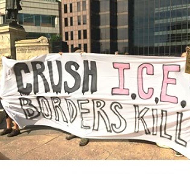 People at rally holding banner reading Crush ICE borders kill