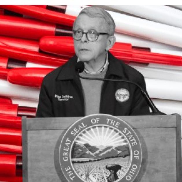 Governor Dewine at a podium in front of red pens