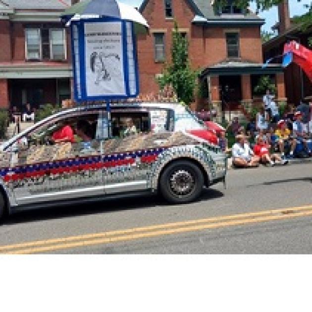 Decorated car and people sitting in front of houses watching