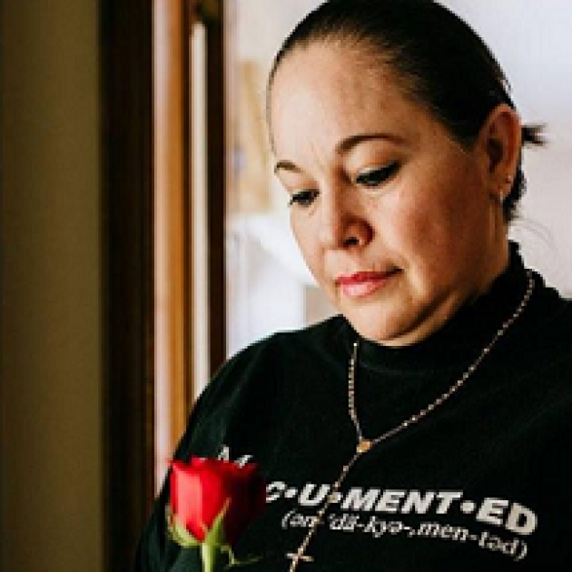Latina woman looking down at a red rose in our hand