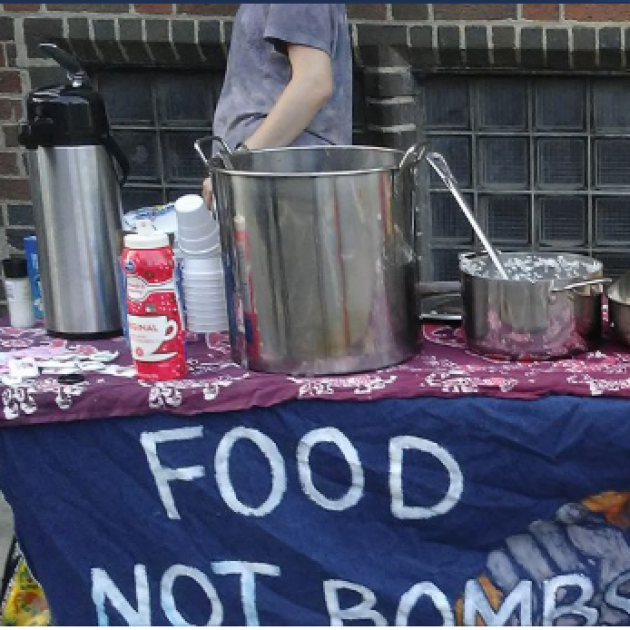 Table with pots and pans and banner saying Food Not Bombs