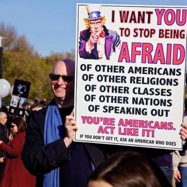 Man outside holding a sign about what Americans fear