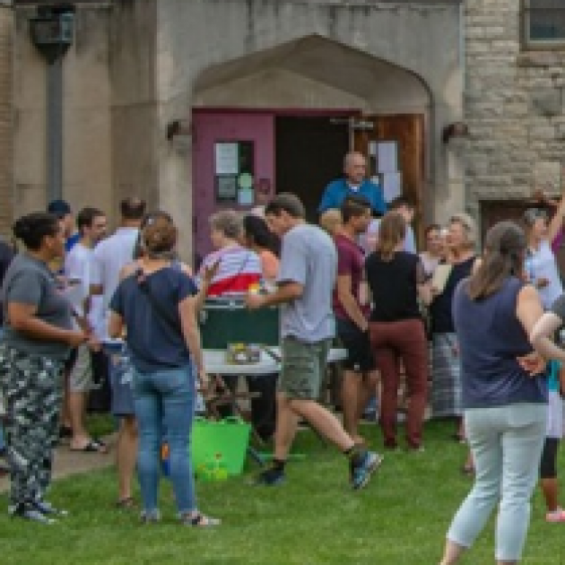 Lots of young people outside the door of a large stone church