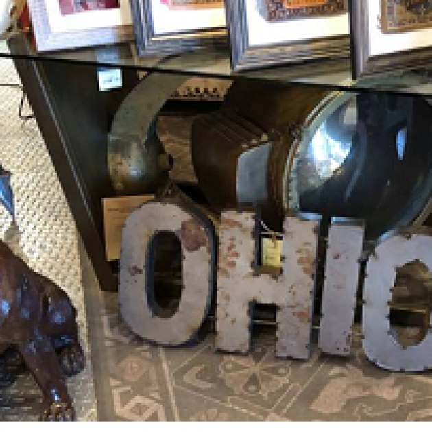A bunch of photos on a shelf and the word Ohio cut out of metal on the floor