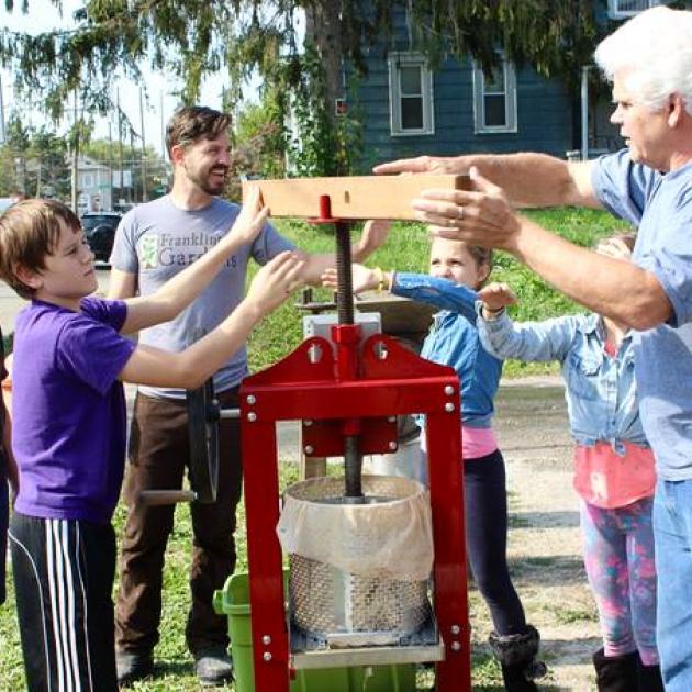 Two young white boys and two men working outside with some sort of garden device