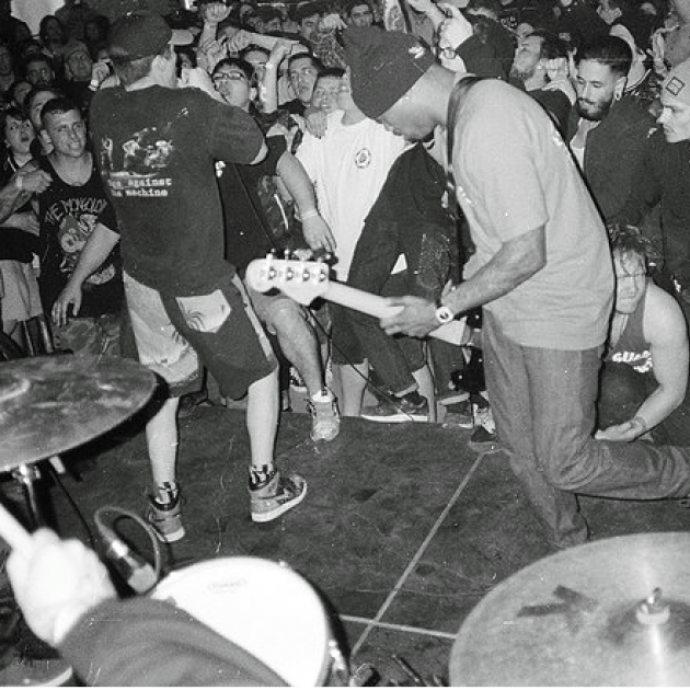 Black and white photo of black guy playing guitar with people all around dancing