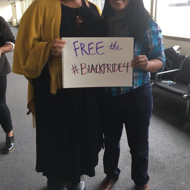 Two people with photo cutting off their heads holding a sign that says Free the Black Pride 4