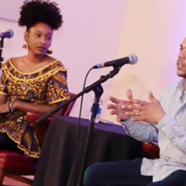 Two people on stage talking into mics