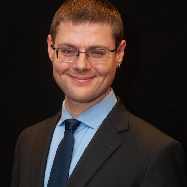 White man in a suit and glasses smiling