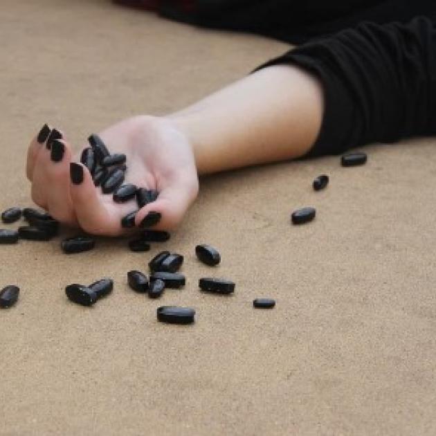 LIfeless hand with pills scarttered around