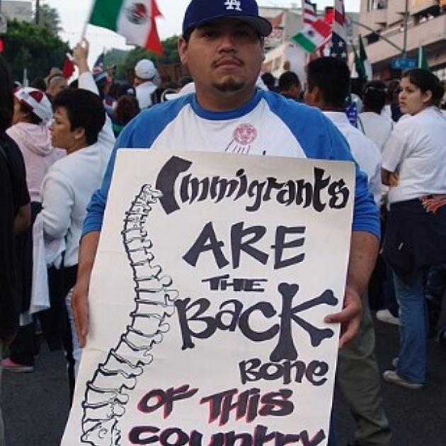 Man holding sign saying Immigrants are the Backbone of this country