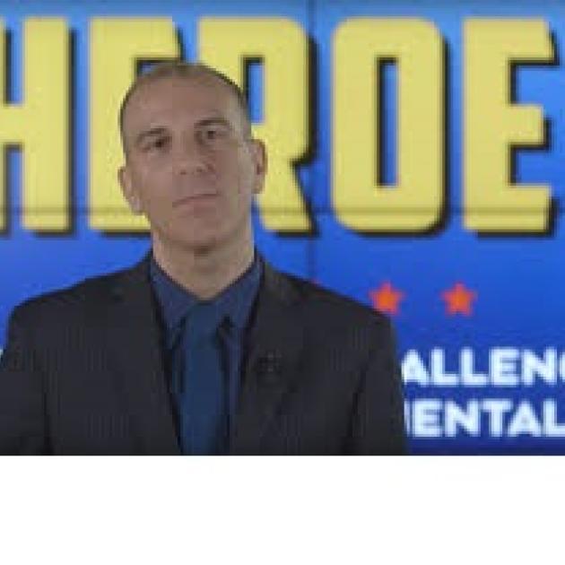 White balding guy against blue background with yellow words saying Heroes