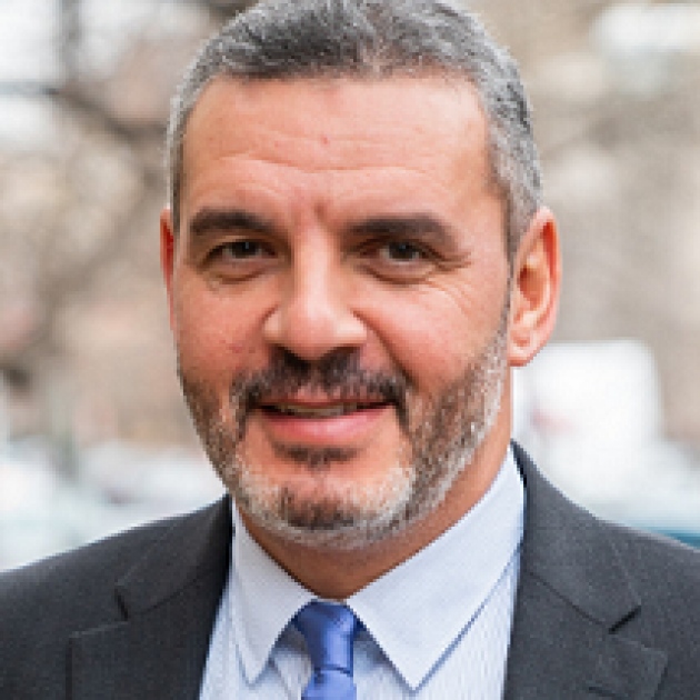 Man with salt and pepper hair and beard in a suit