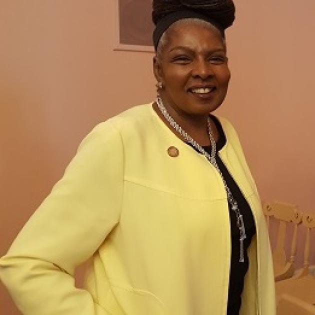 Black woman with updo wearing a yellow suit